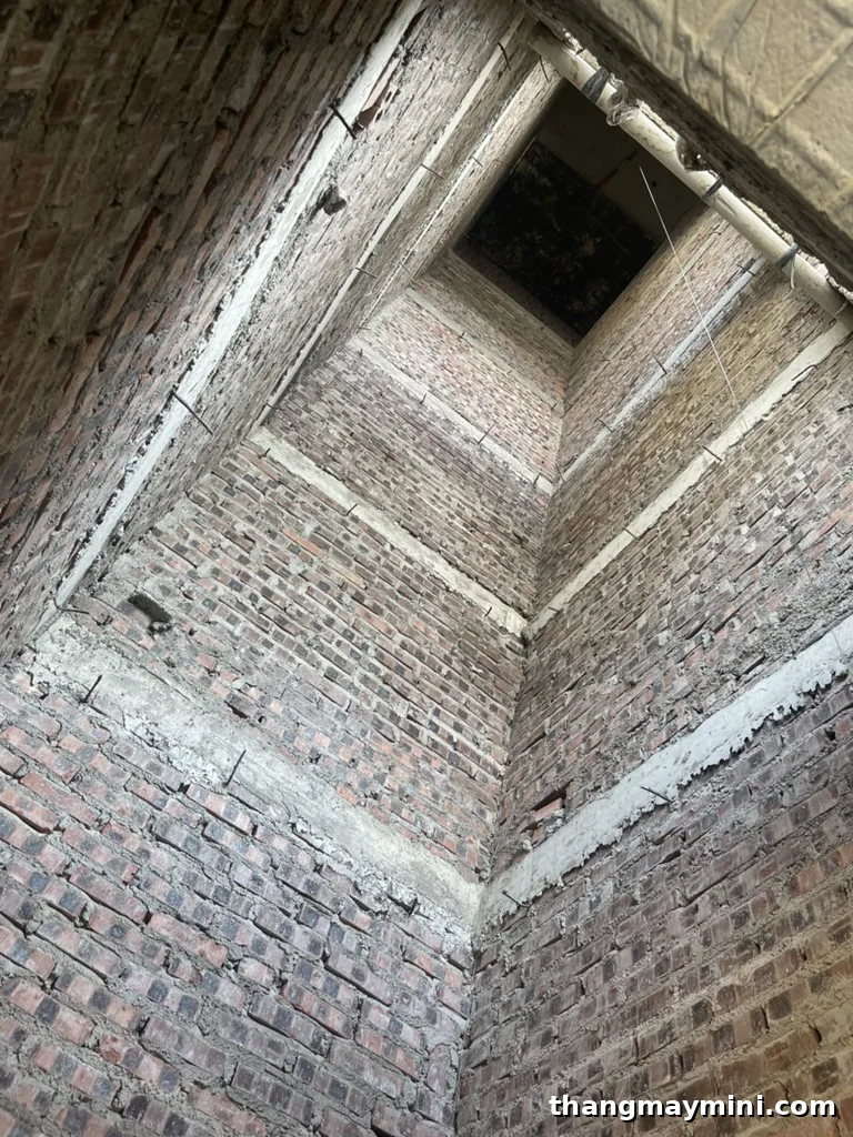 Giếng thang xây gạch của thang máy không phòng máy nhìn từ đáy hố pit lên đỉnh giếng