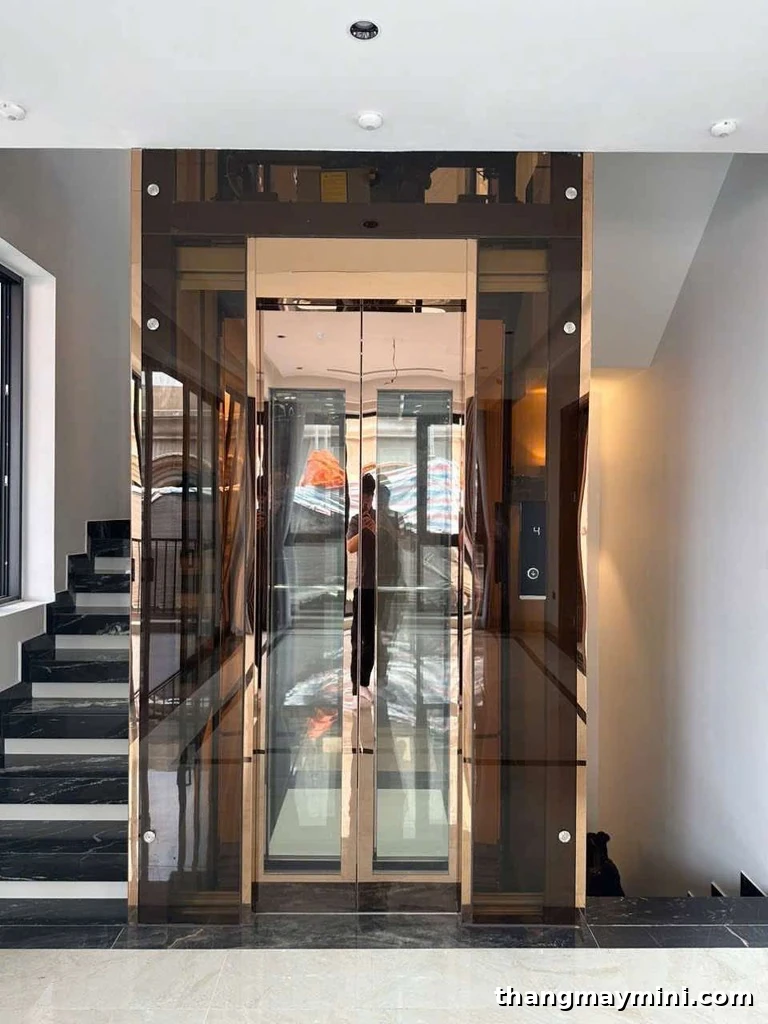 Thang máy không phòng máy cabin vân gỗ lắp cạnh cầu thang trong nhà phố hoàn thiện