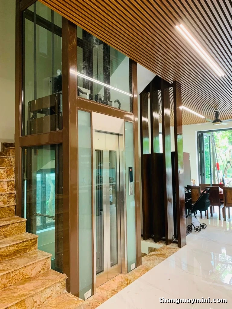 Thang máy kính khung thép lắp trong biệt thự hiện đại trần gỗ