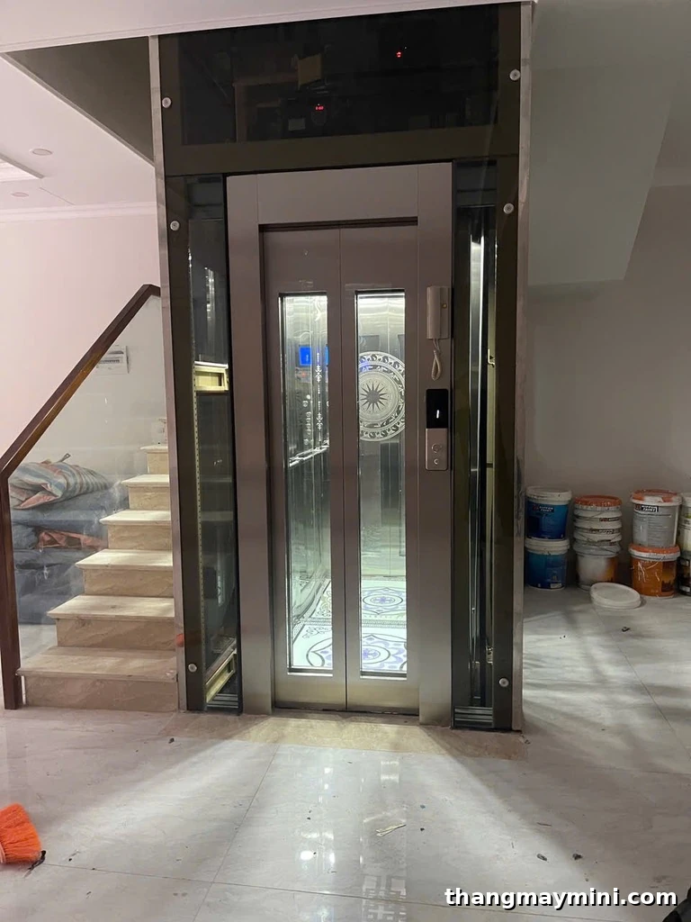 Công trình thực tế thang máy lồng kính cabin inox hoa văn lắp cạnh cầu thang gỗ nhà phố